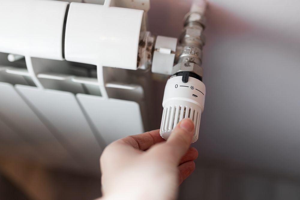 Hand adjusting a radiator thermostatic valve